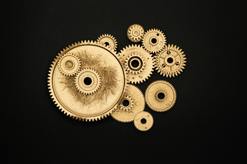 Close-up of golden cogs and gears arranged on a black background showcasing industrial precision.